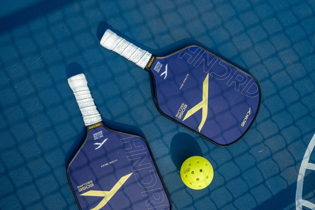 Pickleball paddles and ball on a blue court